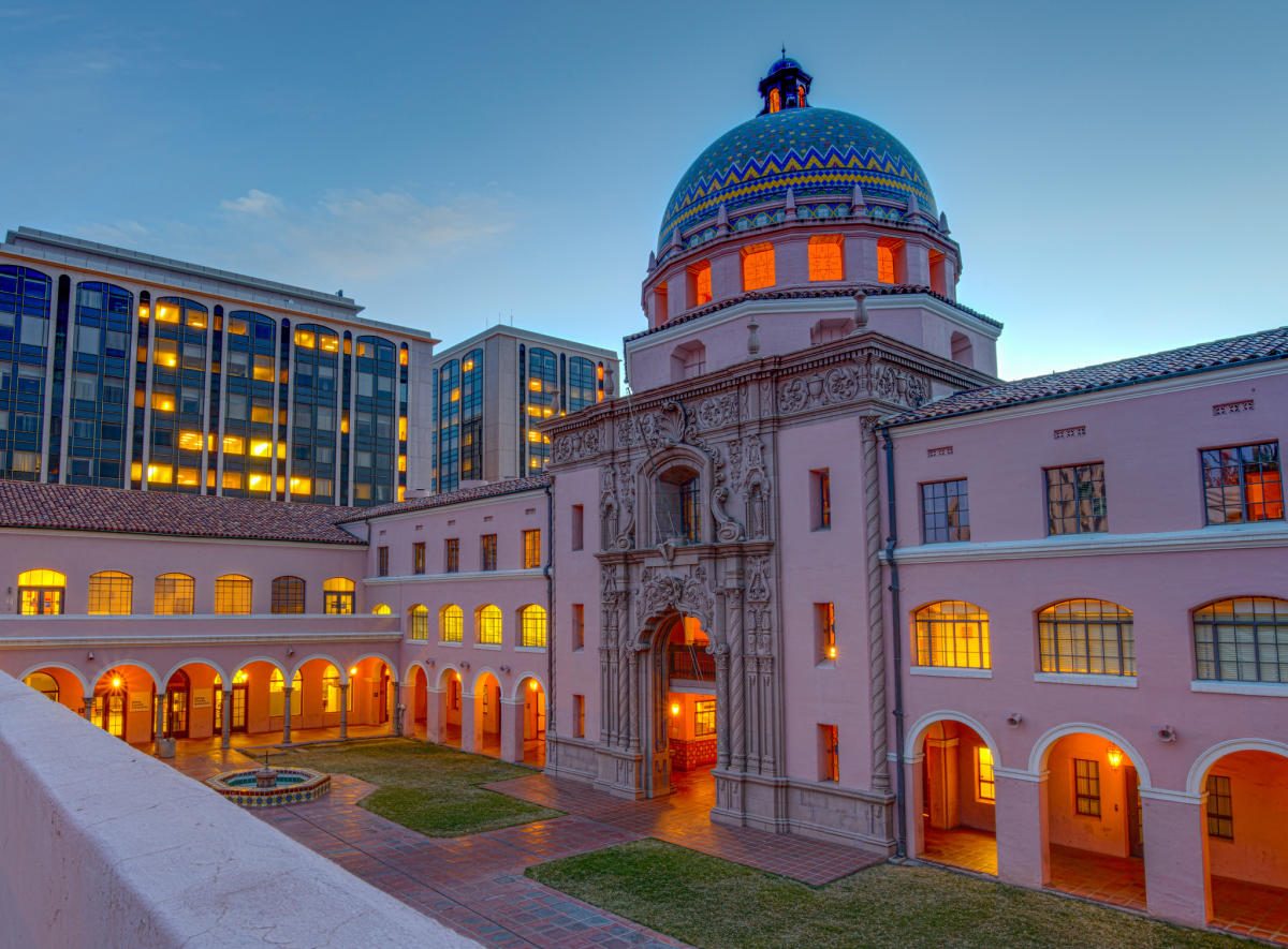 The tiled dome and pink facade of the Pima County Courthouse at dusk