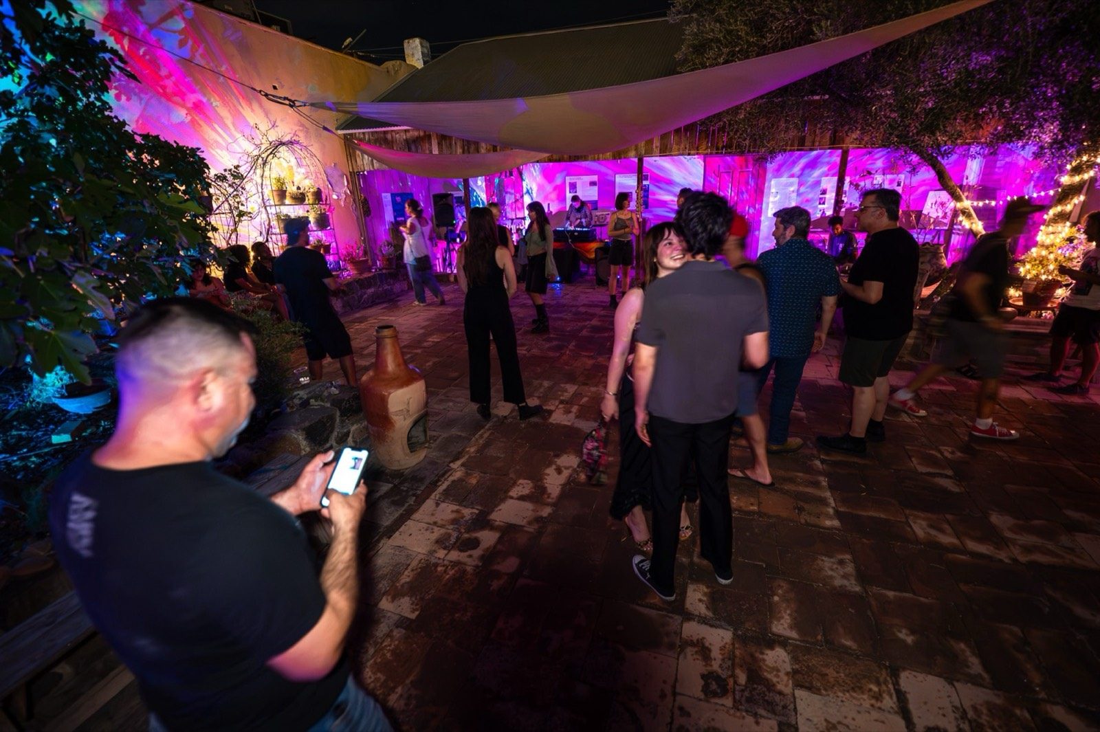 A full patio party bathed in pink light