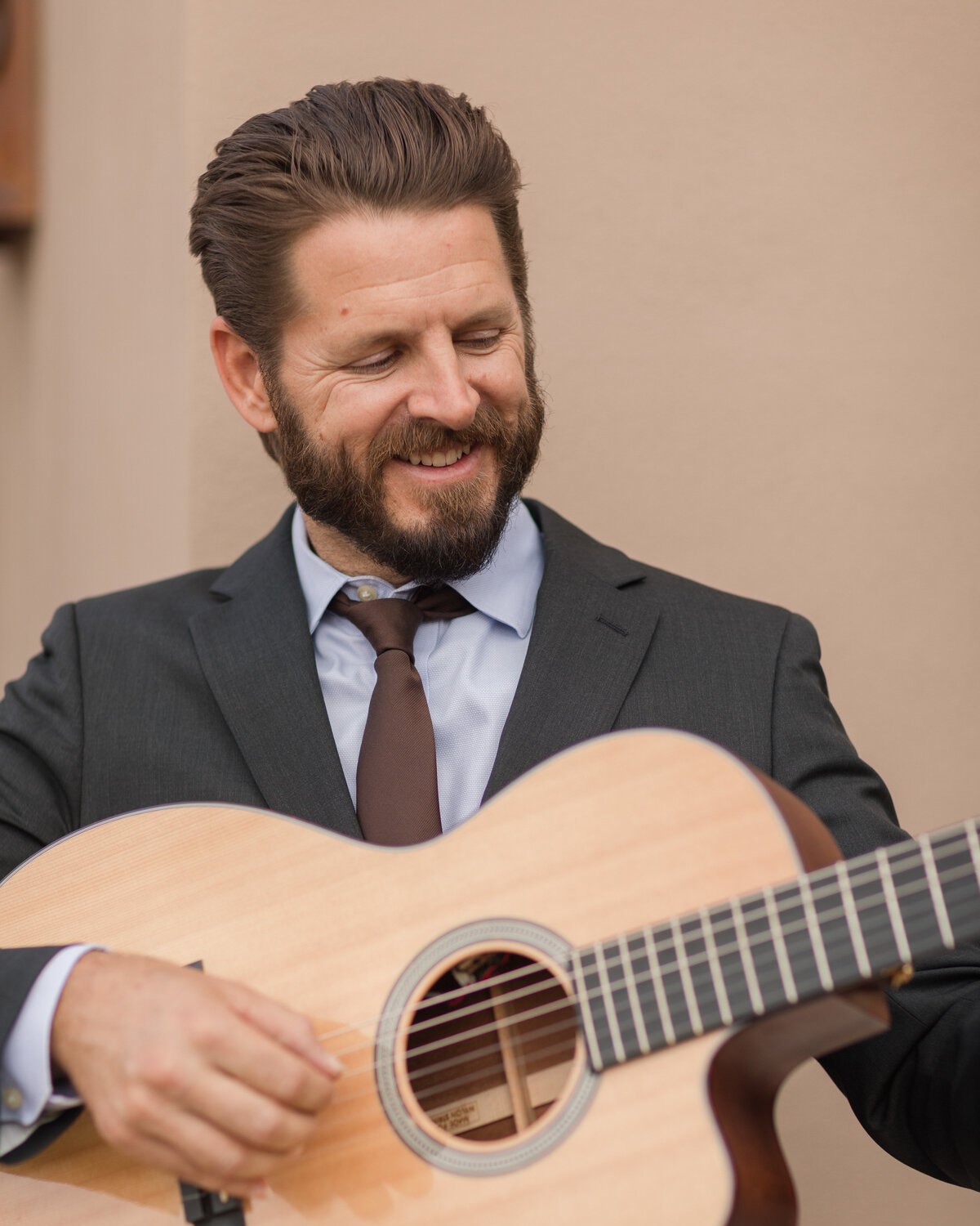 Hans Hutchison in a suit playing guitar at a Tucson wedding ceremony