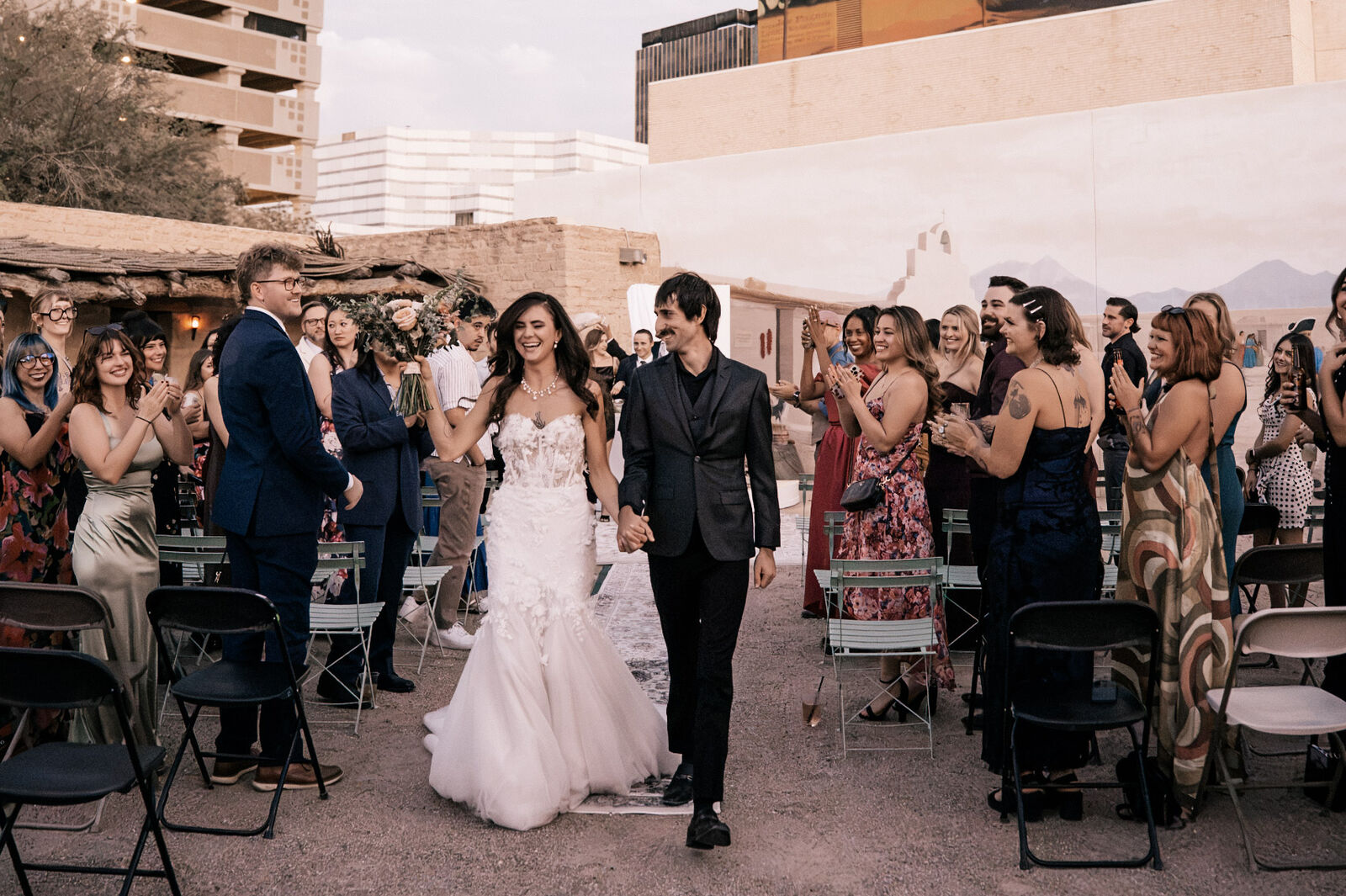 The couple walking out between rows of cheering guests