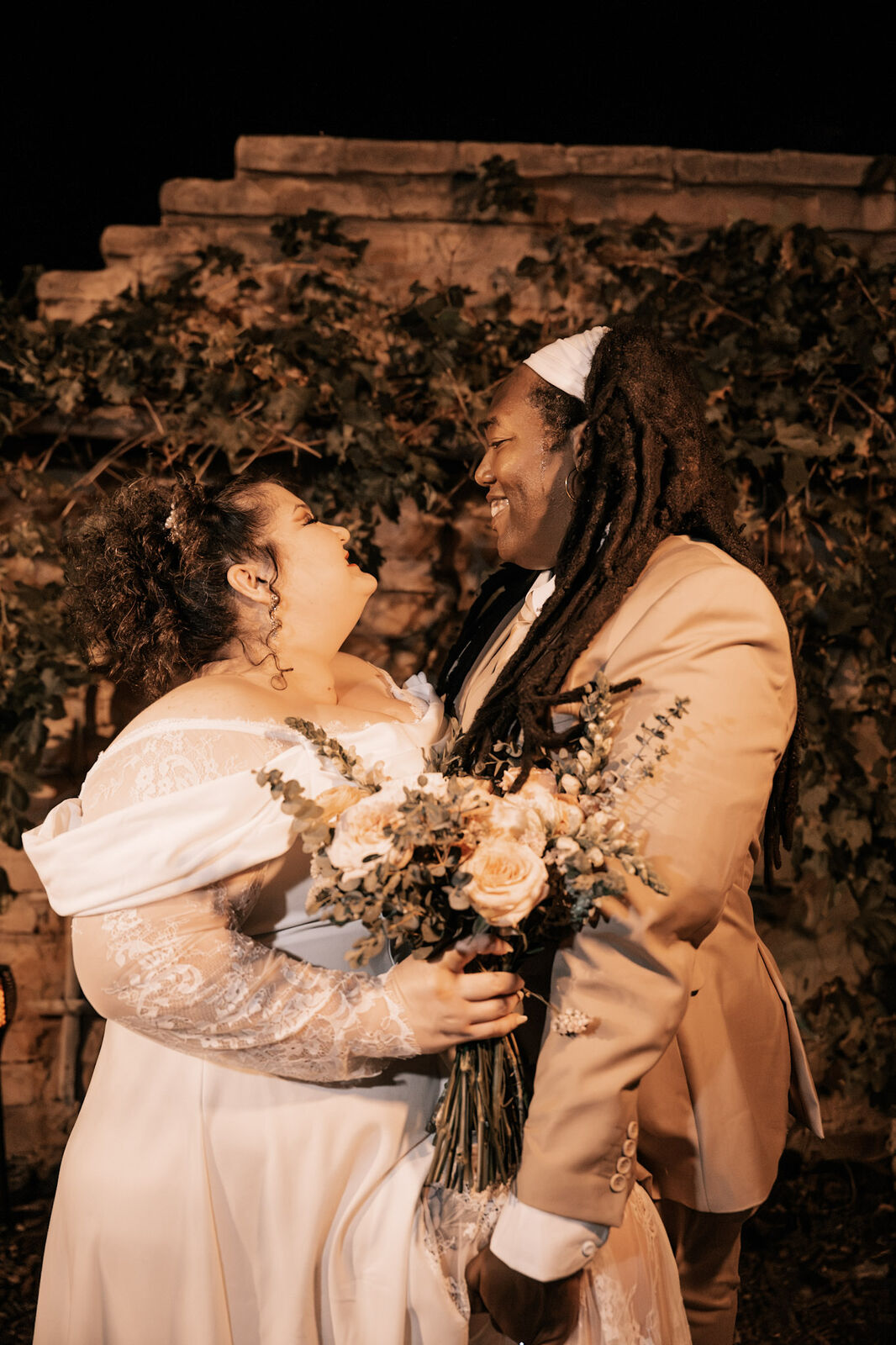 A couple laughing close with the bouquet between them