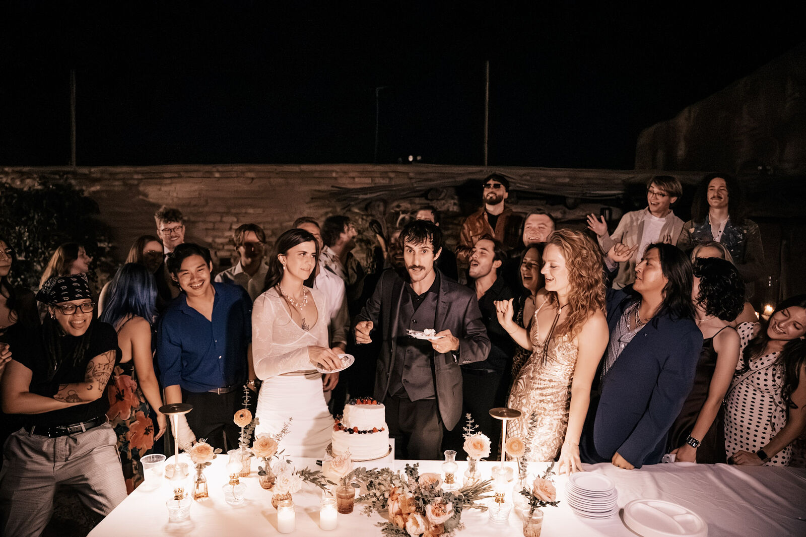 The whole party crowding the cake table, cheering the couple