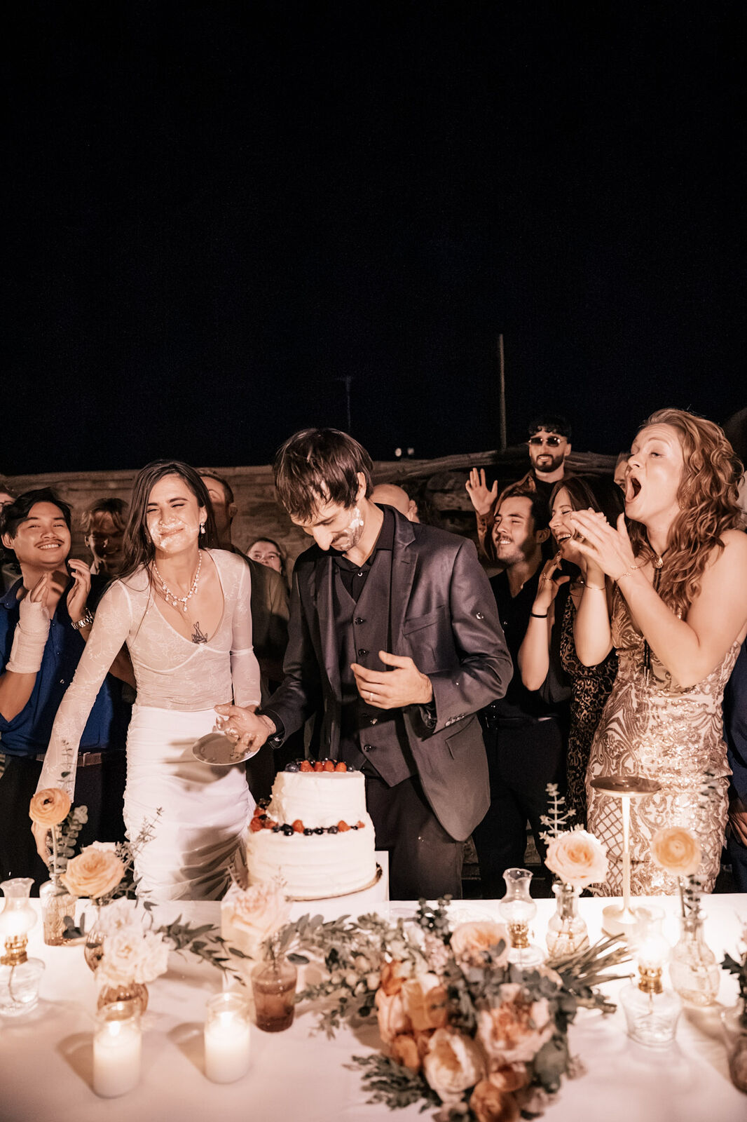 A couple cutting the cake as friends cheer