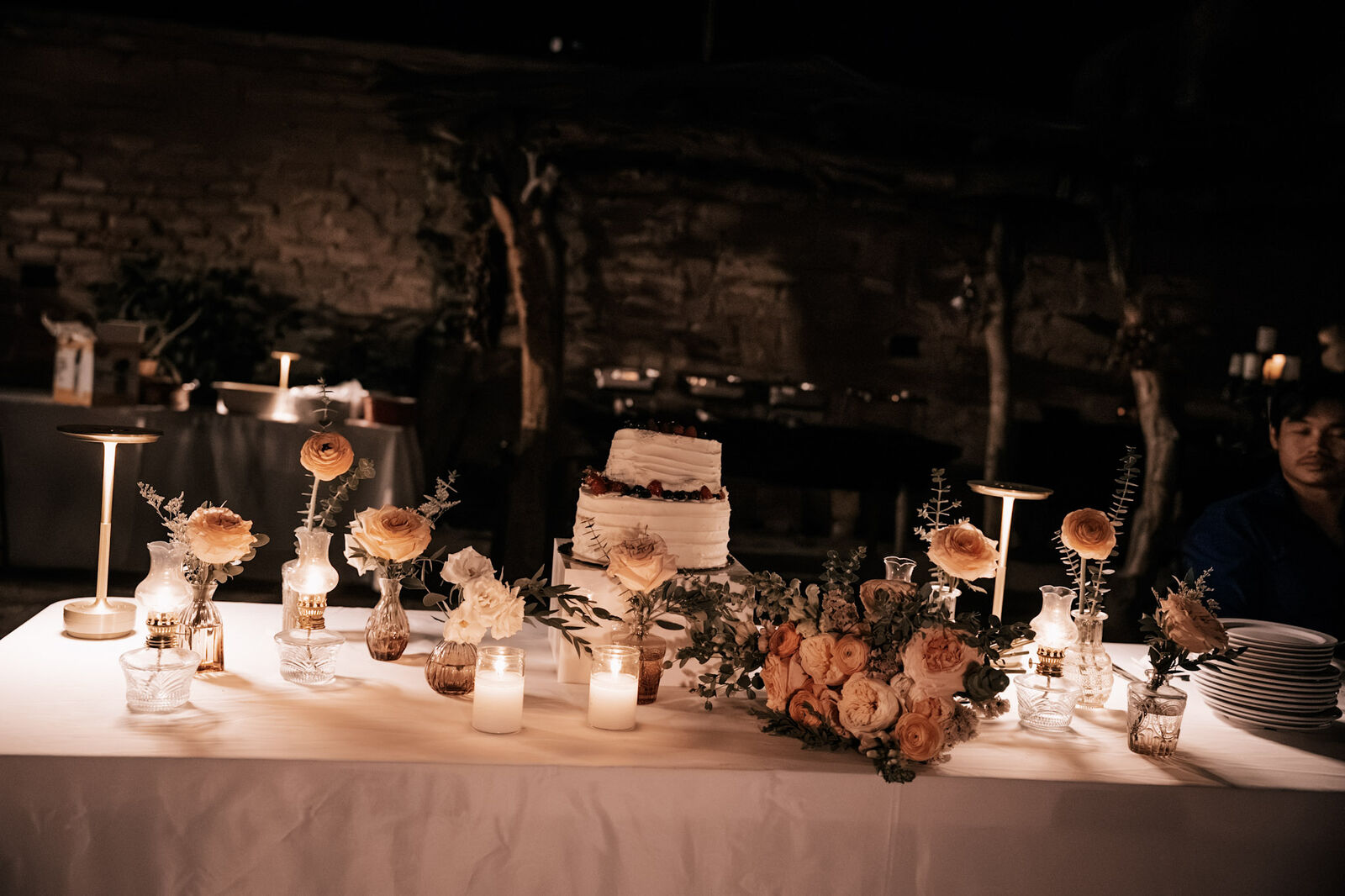 A candlelit cake table dressed with peach flowers