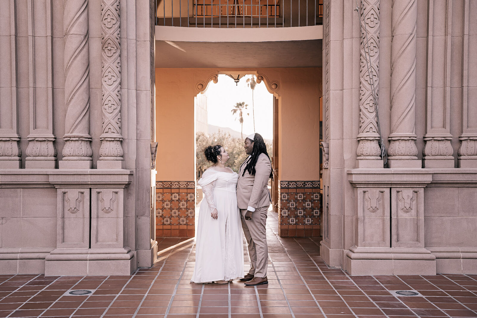 A couple in the arched entry of the Pima County Courthouse on their wedding day