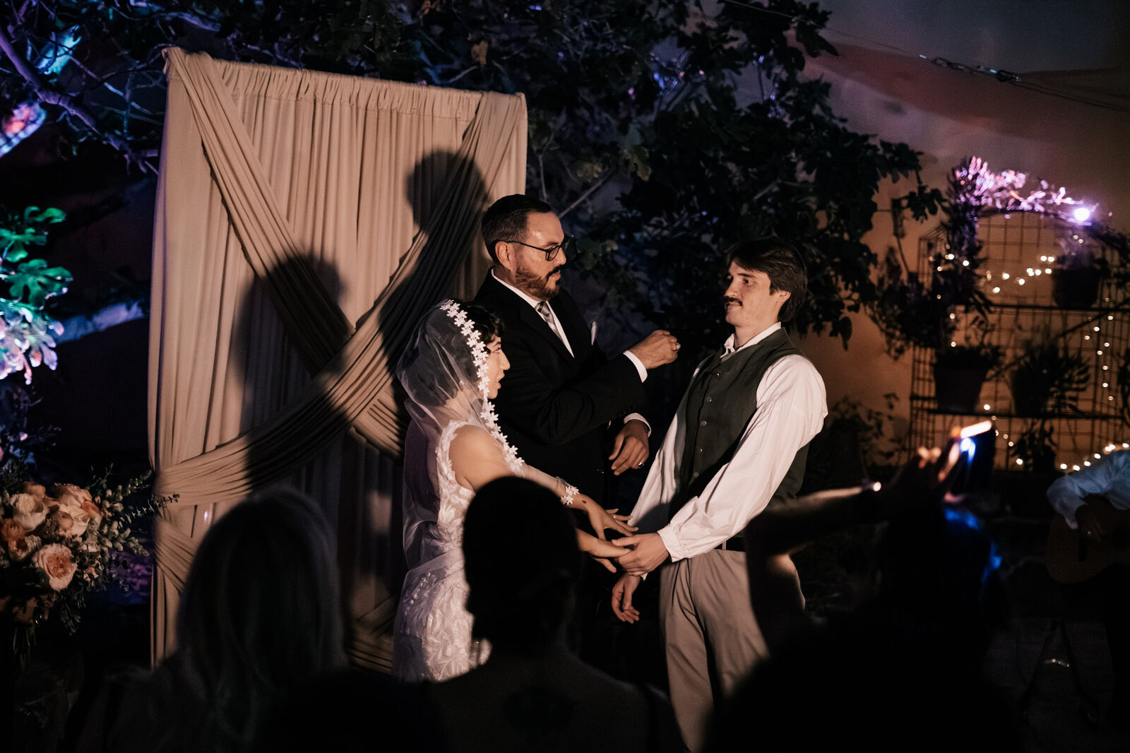 An evening ceremony lit in violet with guests gathered close