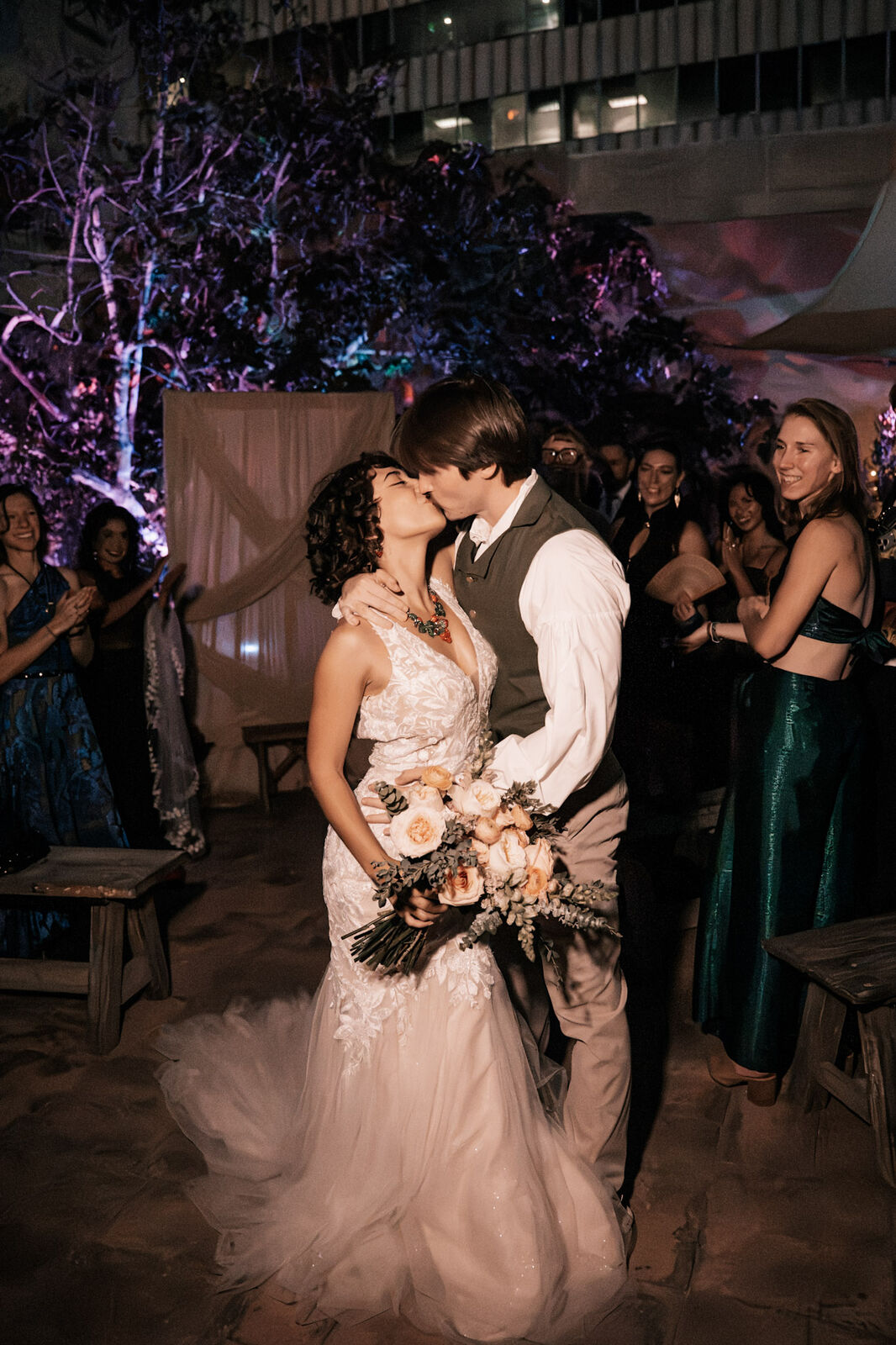 A kiss under purple lights at an evening ceremony