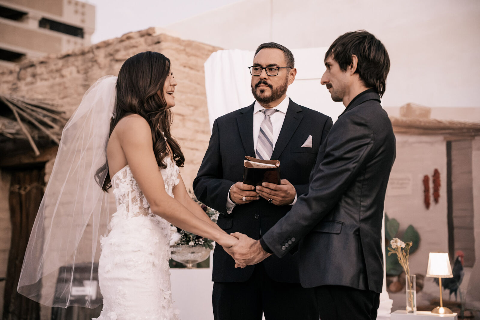 A couple holding hands as their officiant reads the vows in the Presidio courtyard